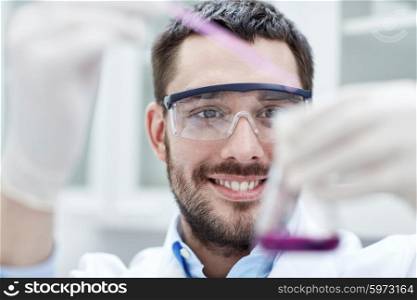 science, chemistry, technology, biology and people concept - young scientist mixing reagents from glass flasks and making test or research in clinical laboratory