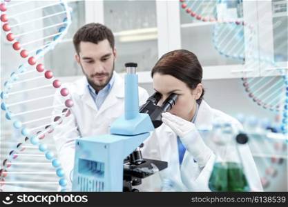 science, chemistry, technology, biology and people concept - young scientists looking to sample through microscope and making test or research in clinical laboratory over dna molecule structure