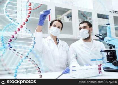 science, chemistry, technology, biology and people concept - young scientists with test tube and microscope making research in clinical laboratory over dna molecule structure