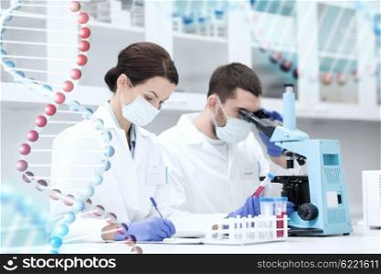 science, chemistry, technology, biology and people concept - young scientists with test tube and microscope making research in clinical laboratory and taking notes over dna molecule structure