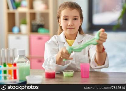 science, childhood and chemistry concept - girl playing with slime at home laboratory. girl playing with slime at home laboratory