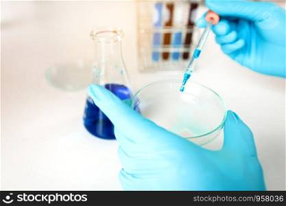 Science doing experiment in laboratory adding liquid in test tube with working on assignment in lab.