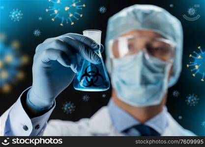 science, medicine and epidemic concept - close up of male scientist wearing goggles and face protective mask holding flask with biohazard sign over coronavirus holograms on black background. close up of scientist and coronavirus hologram