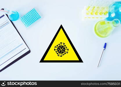 science, medicine and pandemic concept - coronavirus caution sign in scientific laboratory table with test tubes and vaccine samples. coronavirus caution sign in scientific laboratory