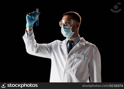 science, medicine, chemistry, research and people concept - young scientist in safety glasses and face mask with test tube. scientist with safety glasses, mask and test tube