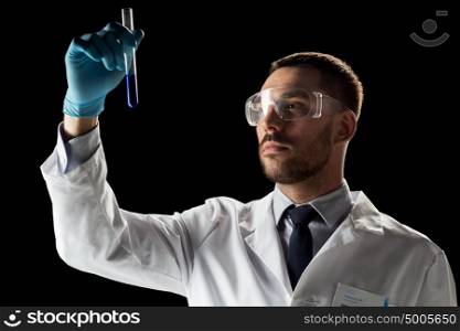 science, medicine, chemistry, research and people concept - young scientist in safety glasses with test tube. scientist in safety glasses with test tube