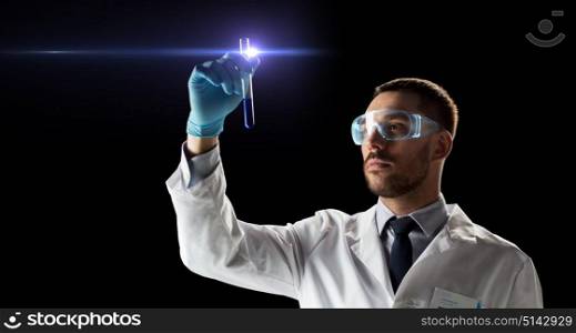 science, research and people concept - young scientist in safety glasses with test tube. scientist in safety glasses with test tube