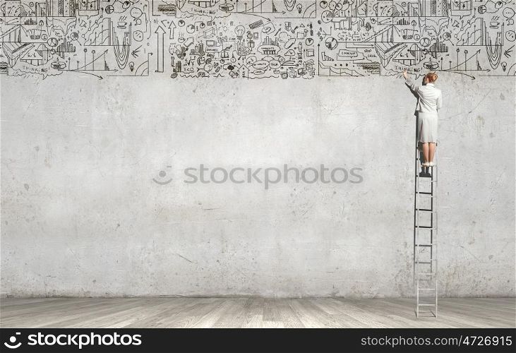 Science research. Rear view of woman standing on ladder and drawing science sketch on wall
