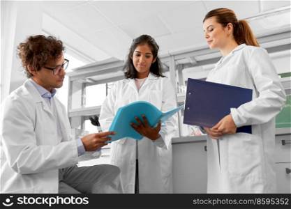 science research, work and people concept - international group of happy scientists with folder discussing report in laboratory. international group of scientists in laboratory