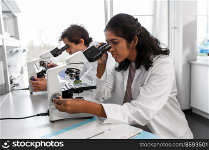 science research, work and people concept - international team of scientists with microscopes working in laboratory. scientists with microscopes working in laboratory