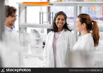 science, work and people concept - international group of happy scientists talking in laboratory. international group of scientists in laboratory