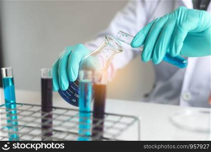 Scientific researcher or doctor pouring chemical substance test tube in laboratory.