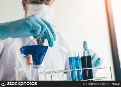 Scientific researcher or doctor pouring chemical substance test tube in laboratory.