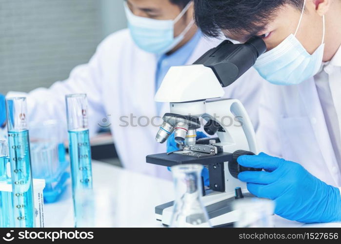 Scientist covid-19 virus antibody sample in laboratory research experiment biotech make cultivate vaccine against virus. Scientist look at microscope, science test tube analyse Chemistry laboratory