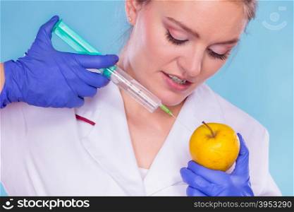 Scientist doctor injecting apple. GM Food.. Scientist doctor injecting apple with syringe. Woman chemist holding genetically modified fruit. GM food modification.