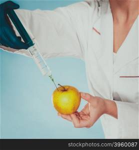 Scientist doctor injecting apple. GM Food.. Scientist doctor injecting apple with syringe. Chemist holding genetically modified fruit. GM food modification.