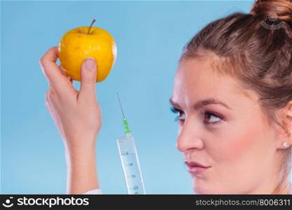 Scientist doctor injecting apple. GM Food.. Scientist doctor injecting apple with syringe. Woman chemist holding genetically modified fruit. GM food modification.