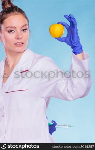 Scientist doctor with apple and syringe. GM Food.. Scientist doctor with apple hiding syringe. Woman chemist holding genetically modified fruit. GM food modification.