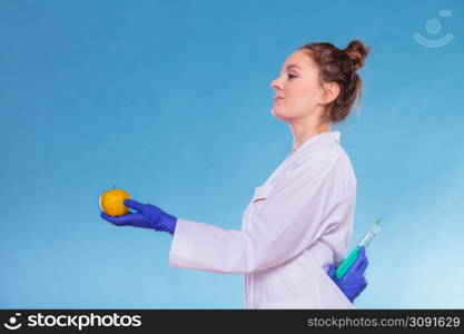 Scientist doctor with apple hiding syringe. Woman chemist holding genetically modified fruit. GM food modification.. Scientist doctor with apple and syringe. GM Food.
