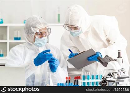Scientist examine vaccine testing of coronavirus covid-19 pandemic in science lab. Scientist wear PPE personal protective suits and medical goggles. Medical Science technology and healthcare concept.