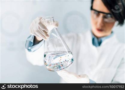 Scientist examining microplastic particles in a water s&le. Microplastic Particles in a Water S&le