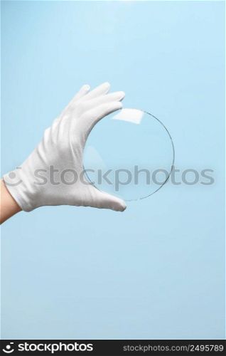 Scientist hand in glove show circle piece of new research prototype of transparent clear glass or plastic material
