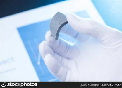 Scientist hold and bend in fingers small piece of gray porous foam, new type of material with different properties research concept