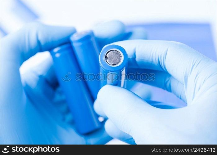 Scientist hold in hand in protective gloves small accumulator battery, new type of rechargable battery research concept