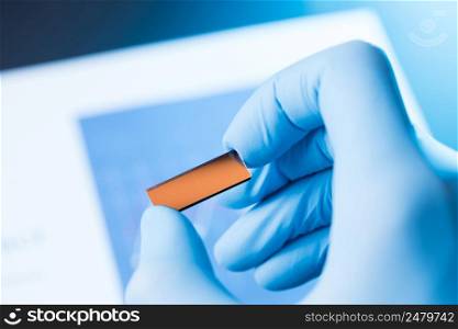 Scientist hold in hand small rectangle tile of new type efficient solar cell tile, solar technology research concept