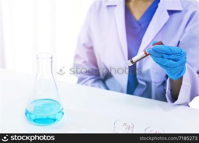 Scientist holding Coronavirus covid-19 infected blood sample tube. DNA testing of the blood in the laboratory with blood sample collection tubes and syringe Coronavirus Covid-19 vaccine research