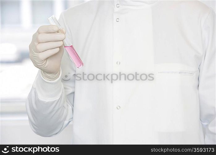 Scientist holding test tube sample, mid-section