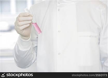 Scientist holding test tube sample, mid-section