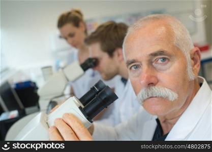 scientist in lab looking through microscope lens
