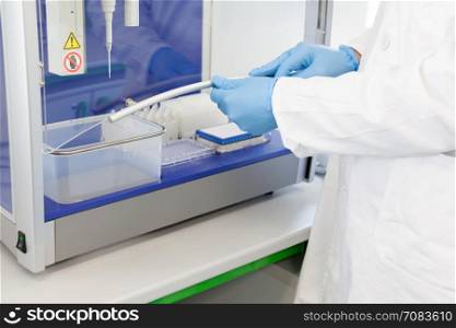 Scientist in laboratory working with automated pipetting system. Liquid handling robot.