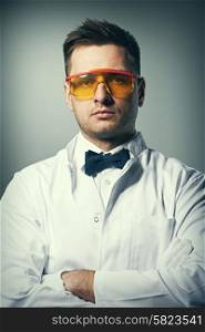 Scientist in yellow glasses against grey background