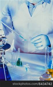 Scientist is doing research at the work, man holds the glass and pipette. Scientist at the work