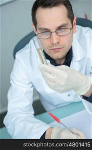 scientist looking at glass tube in lab