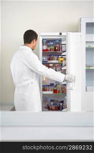 Scientist looking in refrigerator of specimens in laboratory