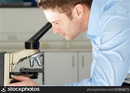 Scientist Looking Through Microscope In Laboratory