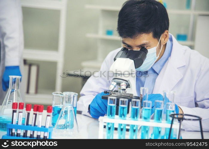 Scientist man look into Microscope research in science laboratory. Asian scientist looking equipment laboratory chemistry labs. Covid-19 coronavirus biochemistry research experiment vaccine concept