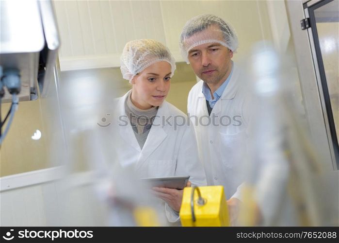 scientist speaking to his colleague holding clipboard in the factory