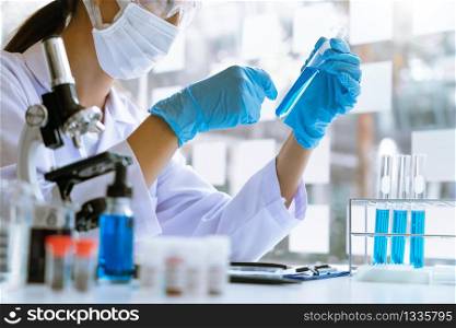 Scientist wear lab coat and protective wear are working with research or doing investigations with test tubes in experiment, Laboratory and development concept.