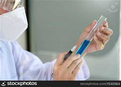 Scientist wear lab coat and protective wear are working with research or doing investigations with test tubes in experiment, Laboratory and development concept.