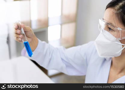 Scientist wear lab coat and protective wear are working with research or doing investigations with test tubes in experiment, Laboratory and development concept.