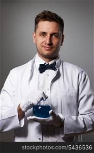 Scientist with chemical flask against grey background