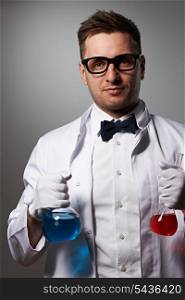Scientist with chemical flasks against grey background