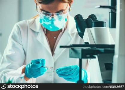 Scientist working in a laboratory, placing microscope slide on the stage