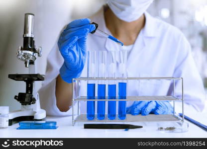 scientists researching in laboratory in white lab coat, gloves analysing, looking at test tubes sample, biotechnology concept.