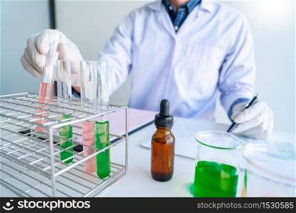scientists researching in laboratory in white lab coat, gloves analysing, looking at test tubes sample, biotechnology concept.