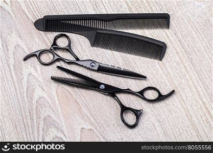 Scissors and comb on white rustic wooden background. Hairdresser salon